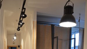 Un couloir étroit doté d’un plancher en bois, d’un mur en briques blanches et d’un comptoir en bois agrémenté d’une plante.
