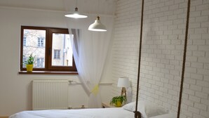 Une chambre à coucher avec un lit, une fenêtre donnant sur un beau paysage, un radiateur et une balançoire suspendue.
