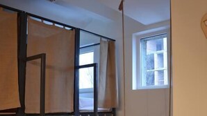 Une chambre avec un lit superposé, une fenêtre, un radiateur et un bureau agrémenté d’une plante.
