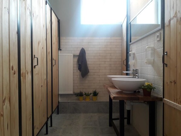 A narrow bathroom with wooden cabinets, a white sink, and a window providing natural light. - Eco Hostel DROVA (Lviv)