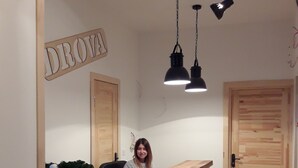 Un comptoir d’accueil au design moderne, avec un mur en briques blanches, des portes en bois et des luminaires suspendus.