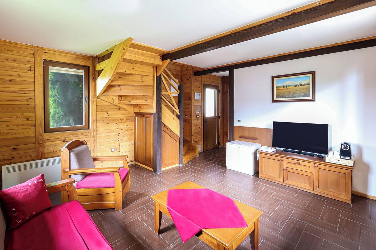 L’intérieur d’un chalet en bois comprend un escalier, un téléviseur et un coin repas.
