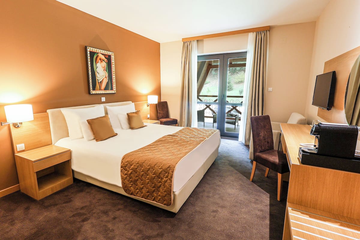 Une chambre d’hôtel avec un grand lit, des tables de chevet, un bureau, une chaise et un téléviseur.