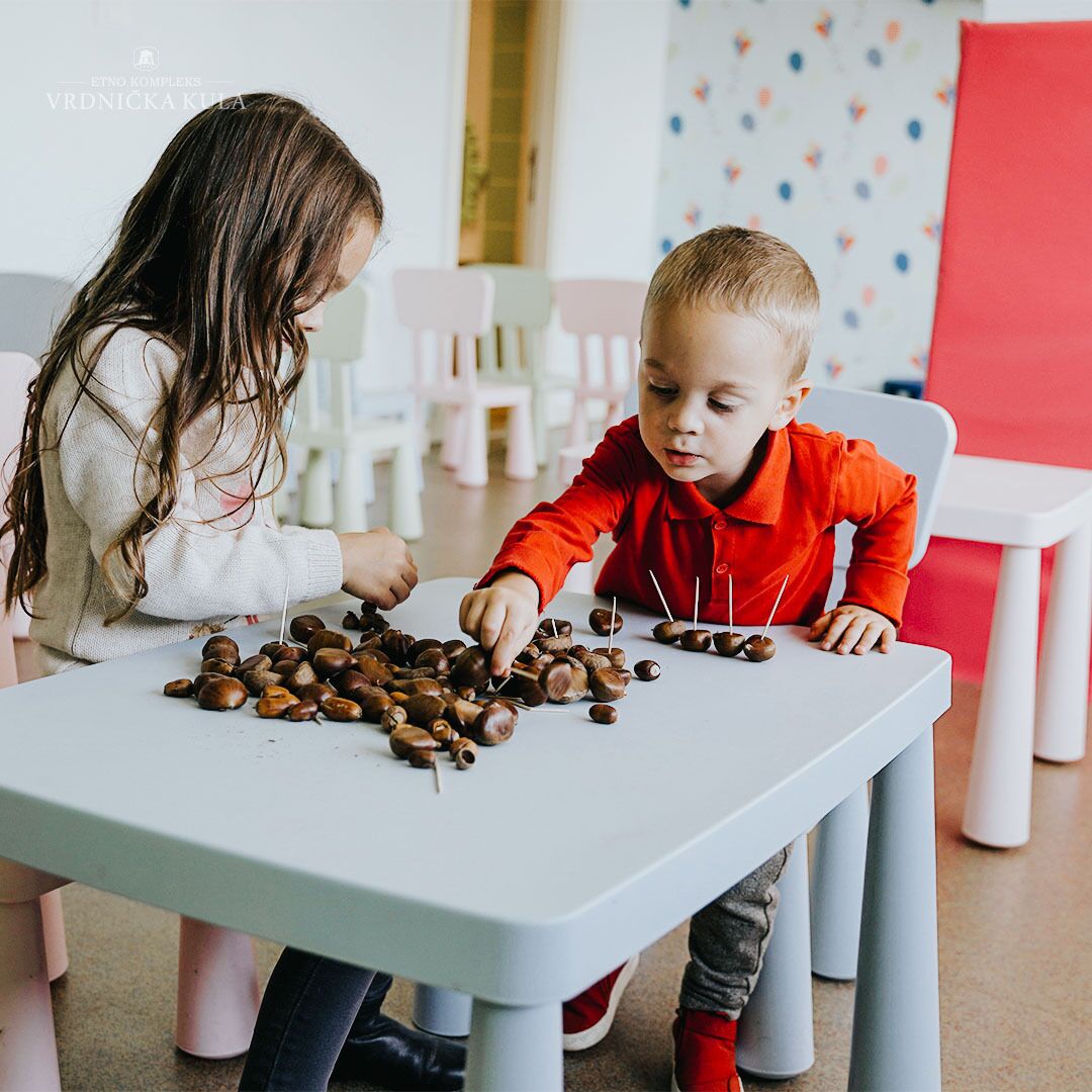 Two children at a table with chestnuts and toothpicks.
