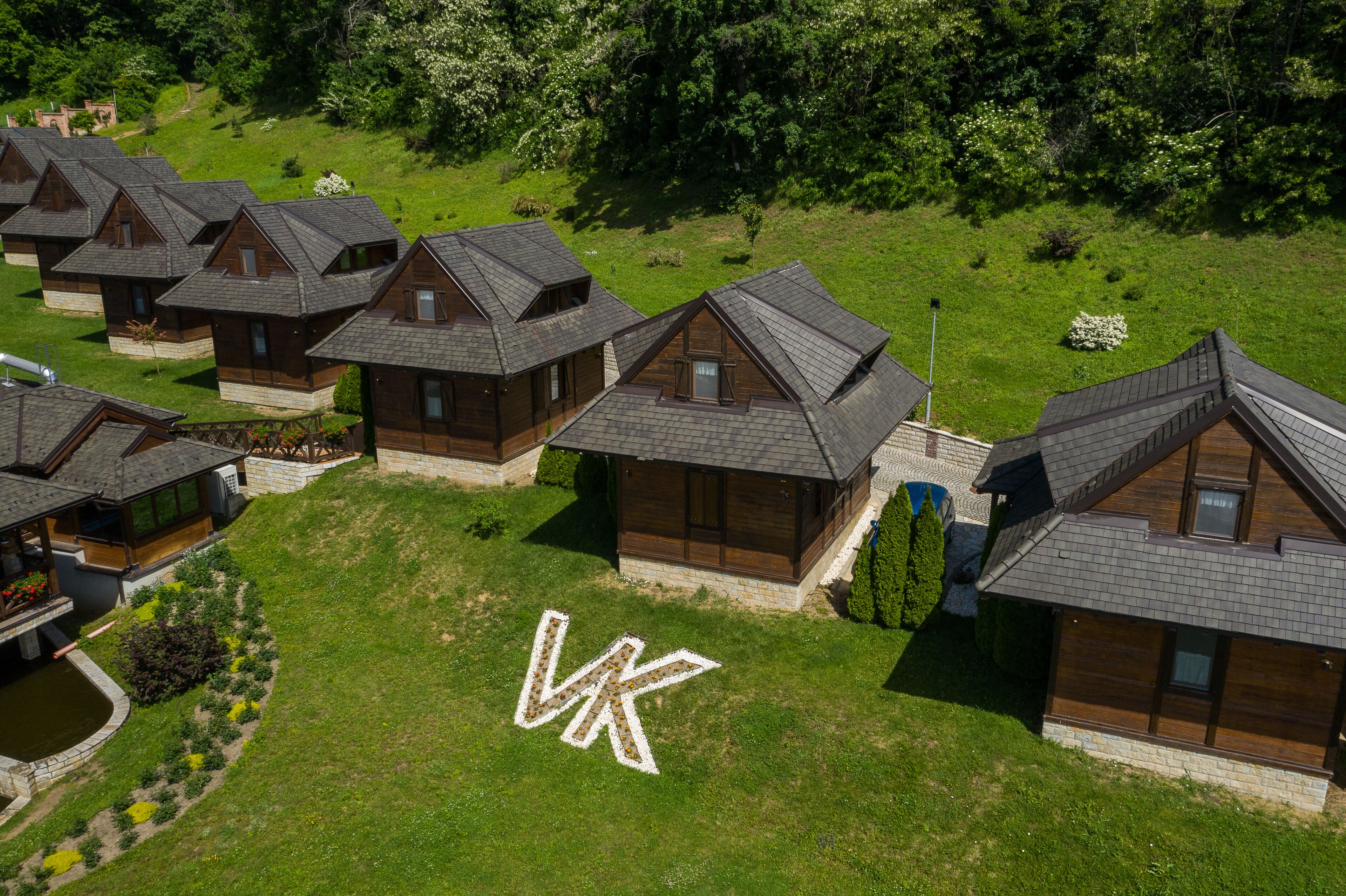 A cluster of wooden cabins with sloped roofs, arranged in a row on a grassy hillside.