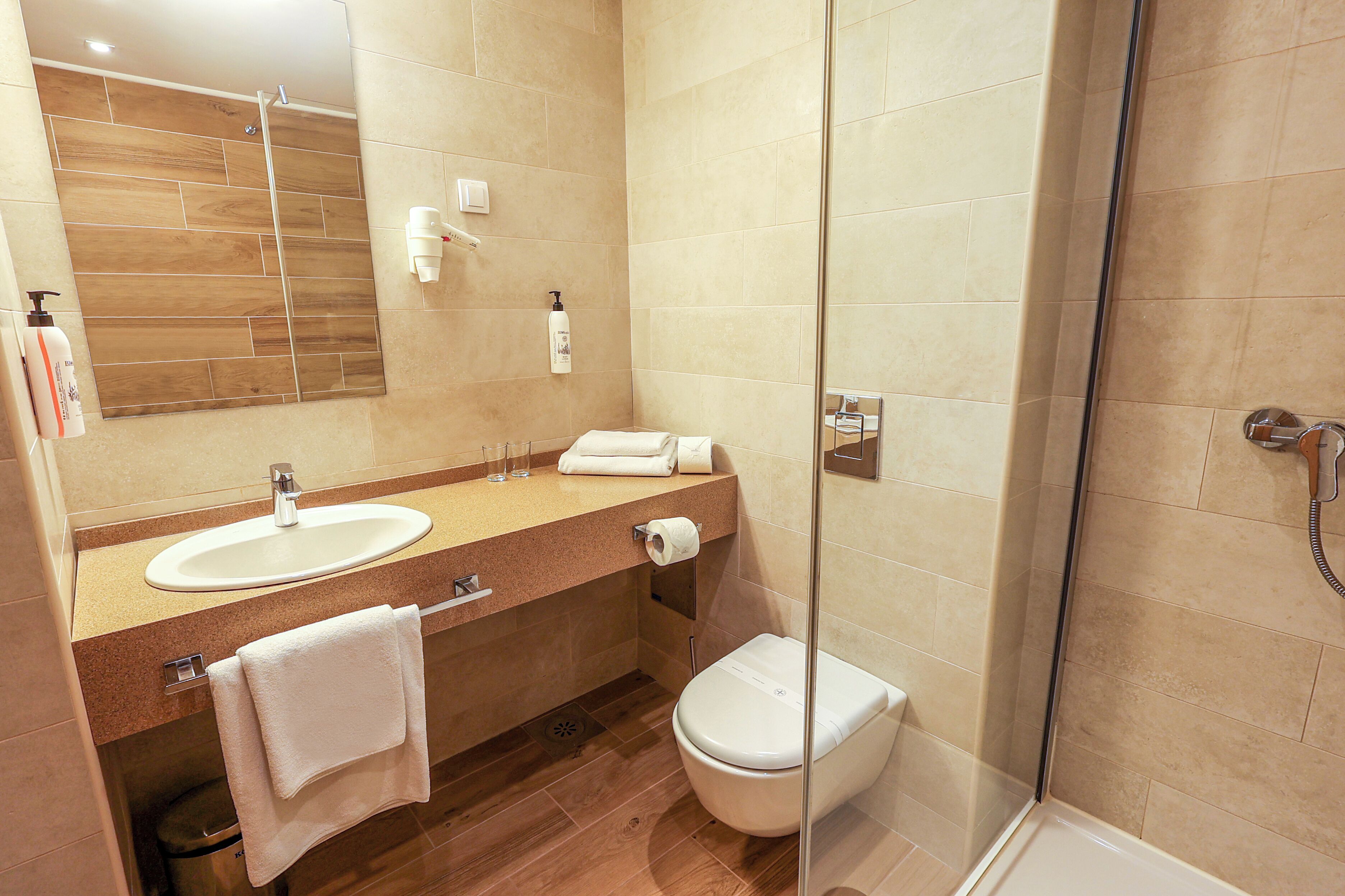 A modern bathroom with a sink, mirror, toilet, and shower.