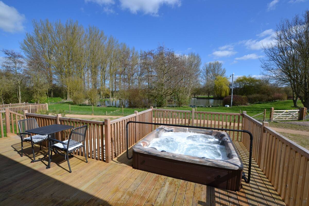 A hot tub on a wooden deck with a view of a park and trees.