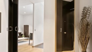A modern interior with a wooden floor, a dark door, and a mirror. - One Bedroom Apartment with balcony (Barcelona)