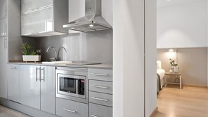 A modern kitchen with grey cabinetry, a built-in oven, and a stainless steel range hood. - One Bedroom Apartment with balcony (Barcelona)