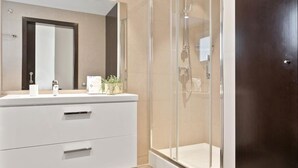 A modern bathroom with a white vanity, a large mirror, and a glass-enclosed shower area. - One Bedroom Apartment with balcony (Barcelona)