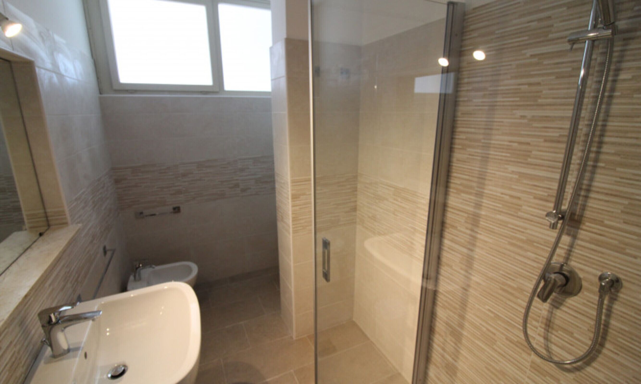 A modern bathroom with a glass-enclosed shower, a sink, and a toilet.