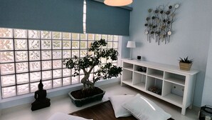 A room with a large window, a potted tree, a meditation statue, a white console table, and a hanging light fixture. - Villa Palmela in Serra da Arrábida (Palmela)