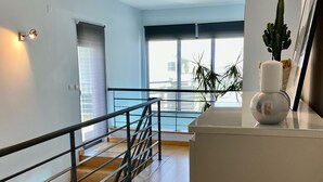 A modern interior with a staircase, a railing, and a view through a window. - Villa Palmela in Serra da Arrábida (Palmela)