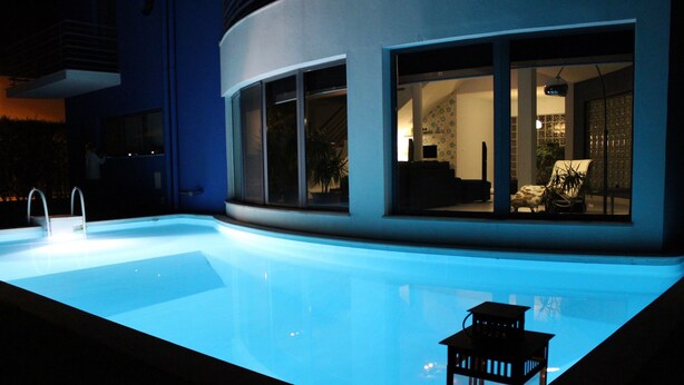 A modern building with a swimming pool, large windows, and a small outdoor seating area. - Villa Palmela in Serra da Arrábida (Palmela)
