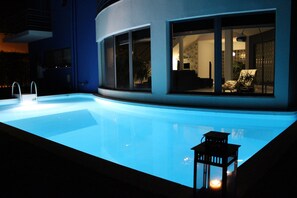 A modern building with a swimming pool, large windows, and a small outdoor seating area. - Villa Palmela in Serra da Arrábida (Palmela)