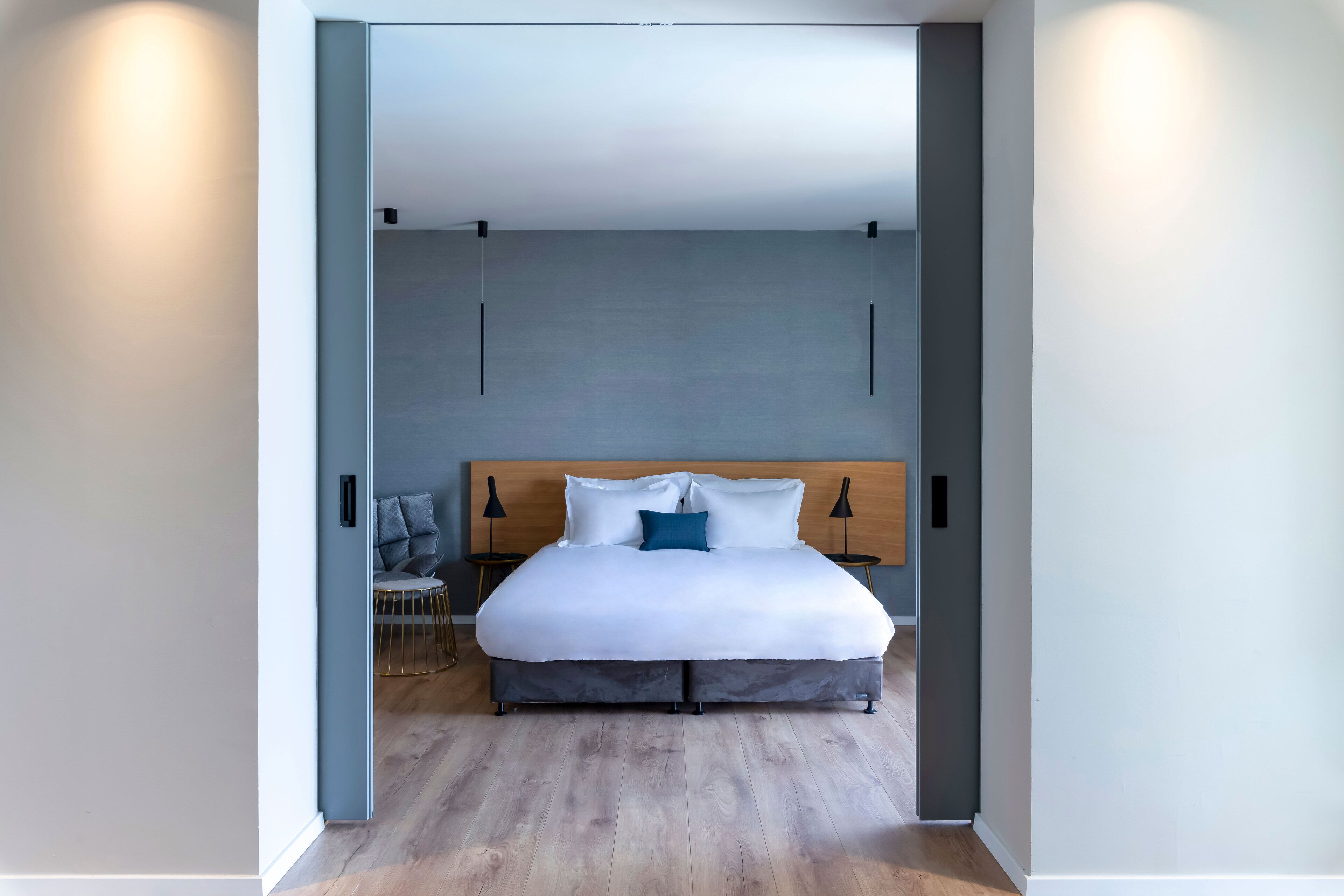Ein modernes Schlafzimmer mit einem großen Bett, einem hölzernen Kopfteil und einer grauen Wand.