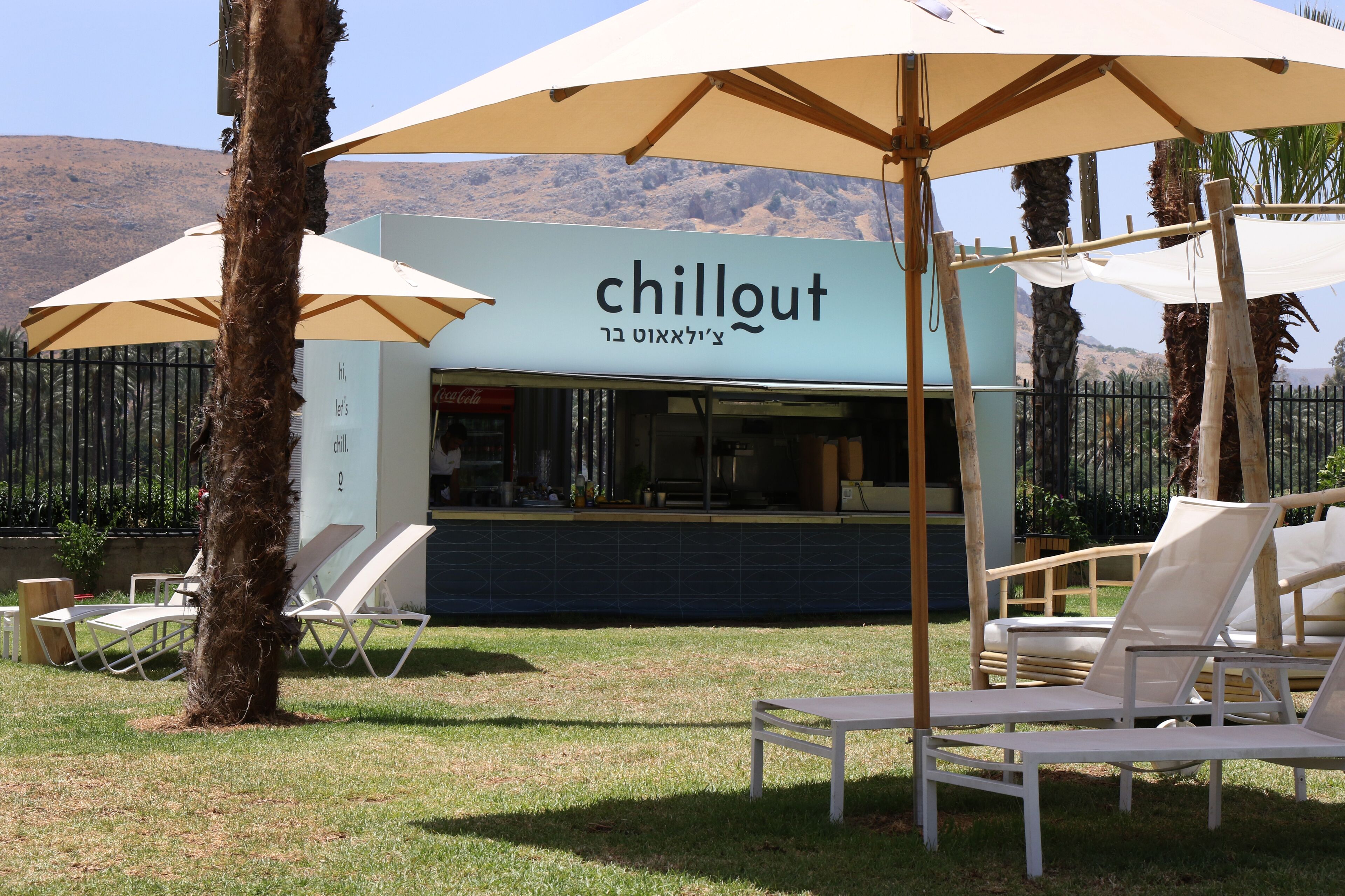 A 'chillout' area with outdoor seating and umbrellas, a counter, and a view of mountains.