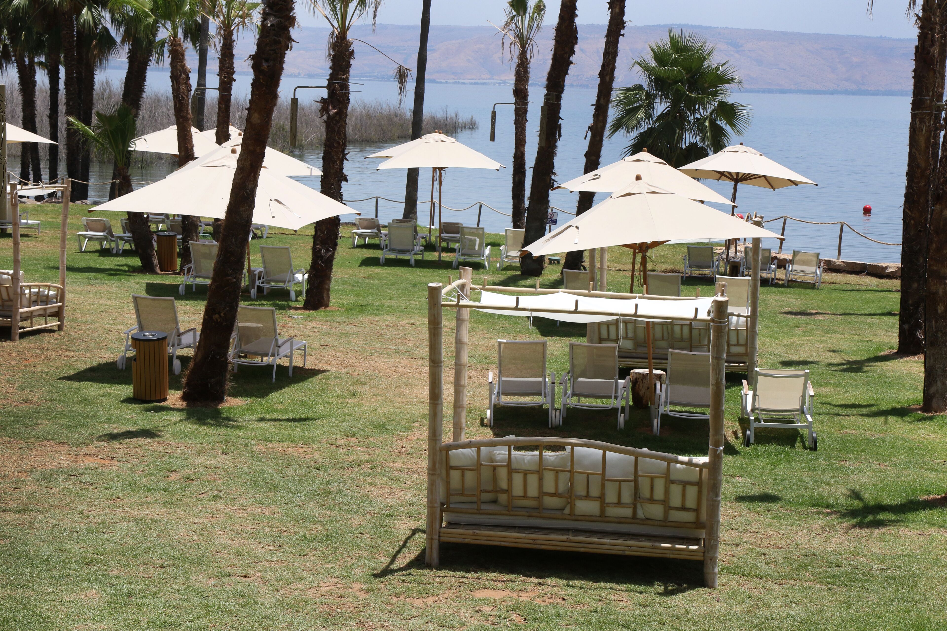 A beachside lounge area with outdoor seating, including chairs and umbrellas, overlooking a body of water.