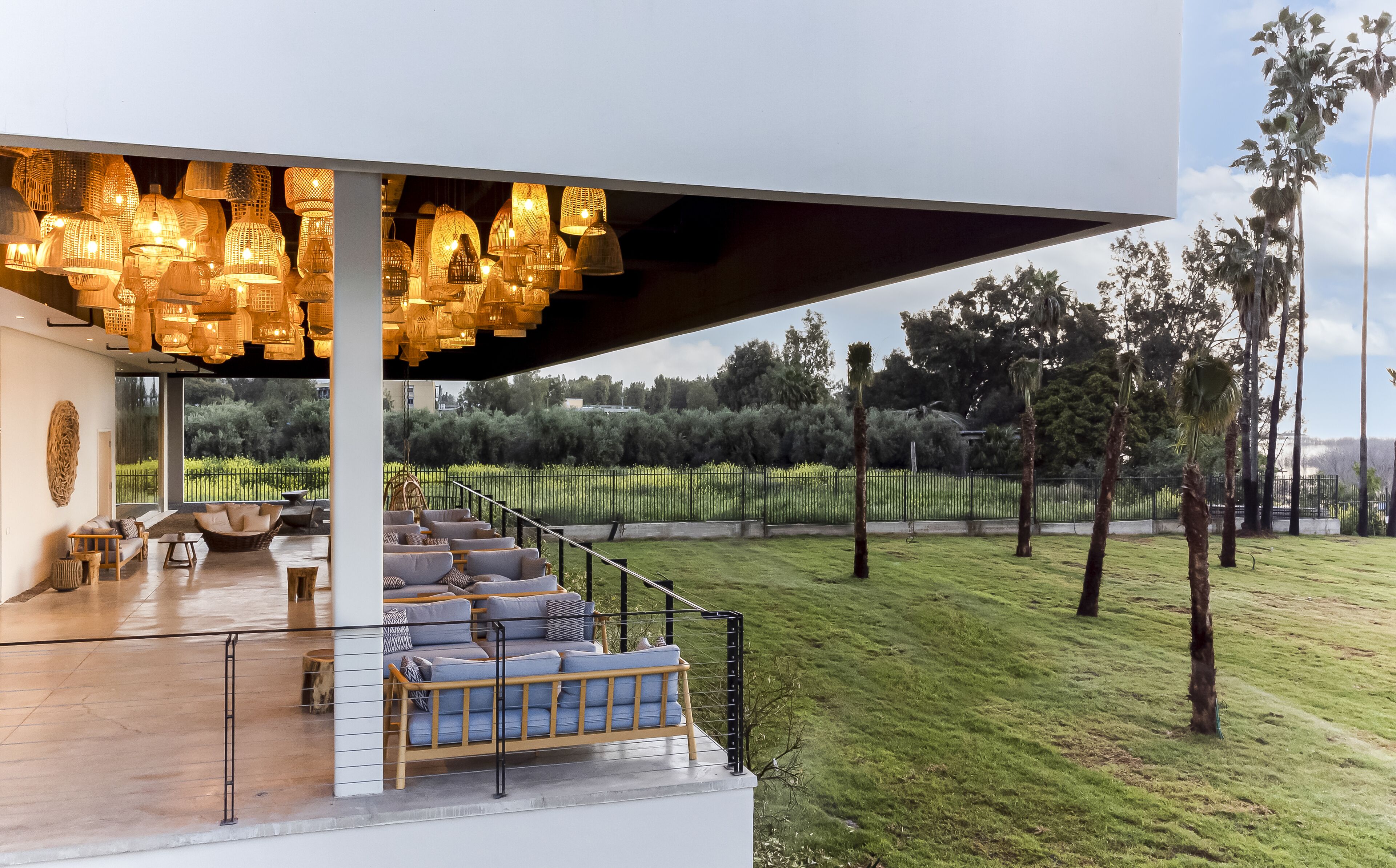 A modern outdoor seating area with wicker furniture and a view of a landscaped garden.