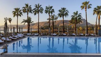 Una piscina techada, una piscina al aire libre, sombrillas