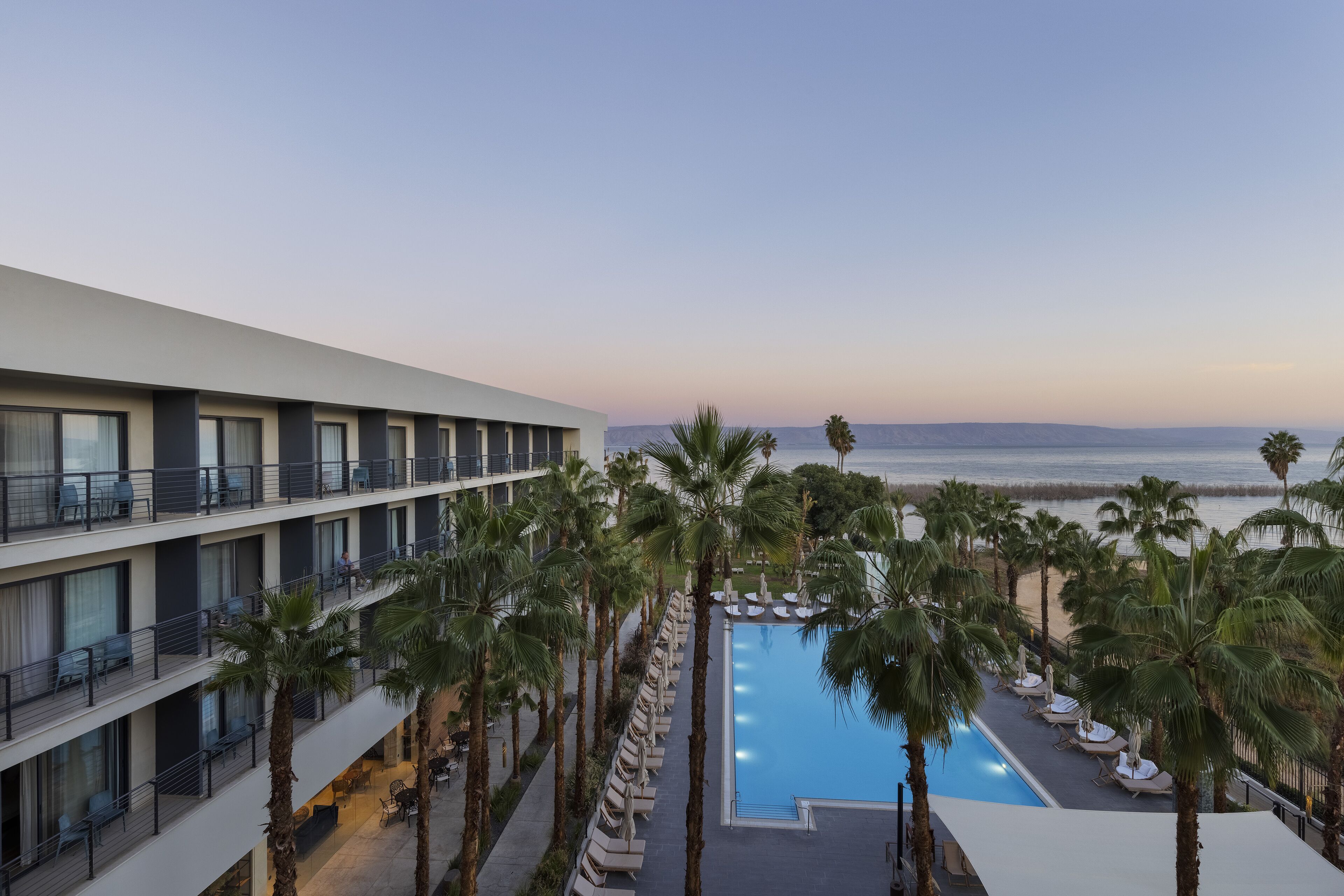 Un hotel con piscina, circondato da palme e vista sull'oceano.