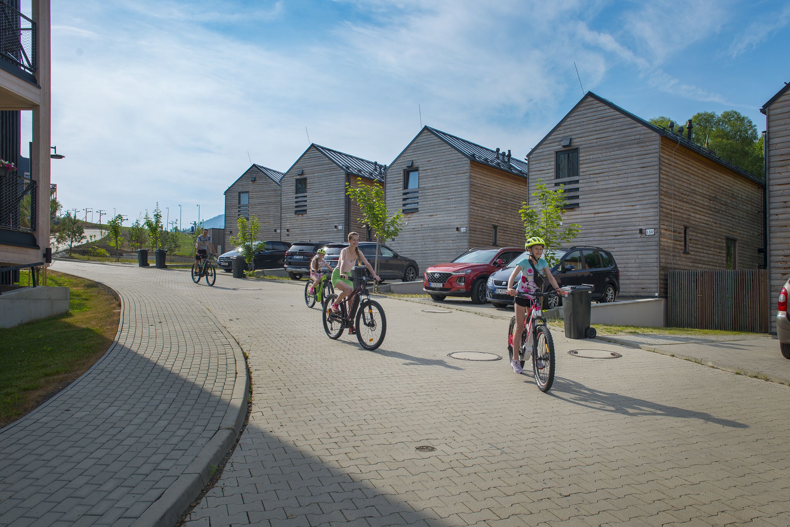 A residential street with houses, bicycles, and parked cars.