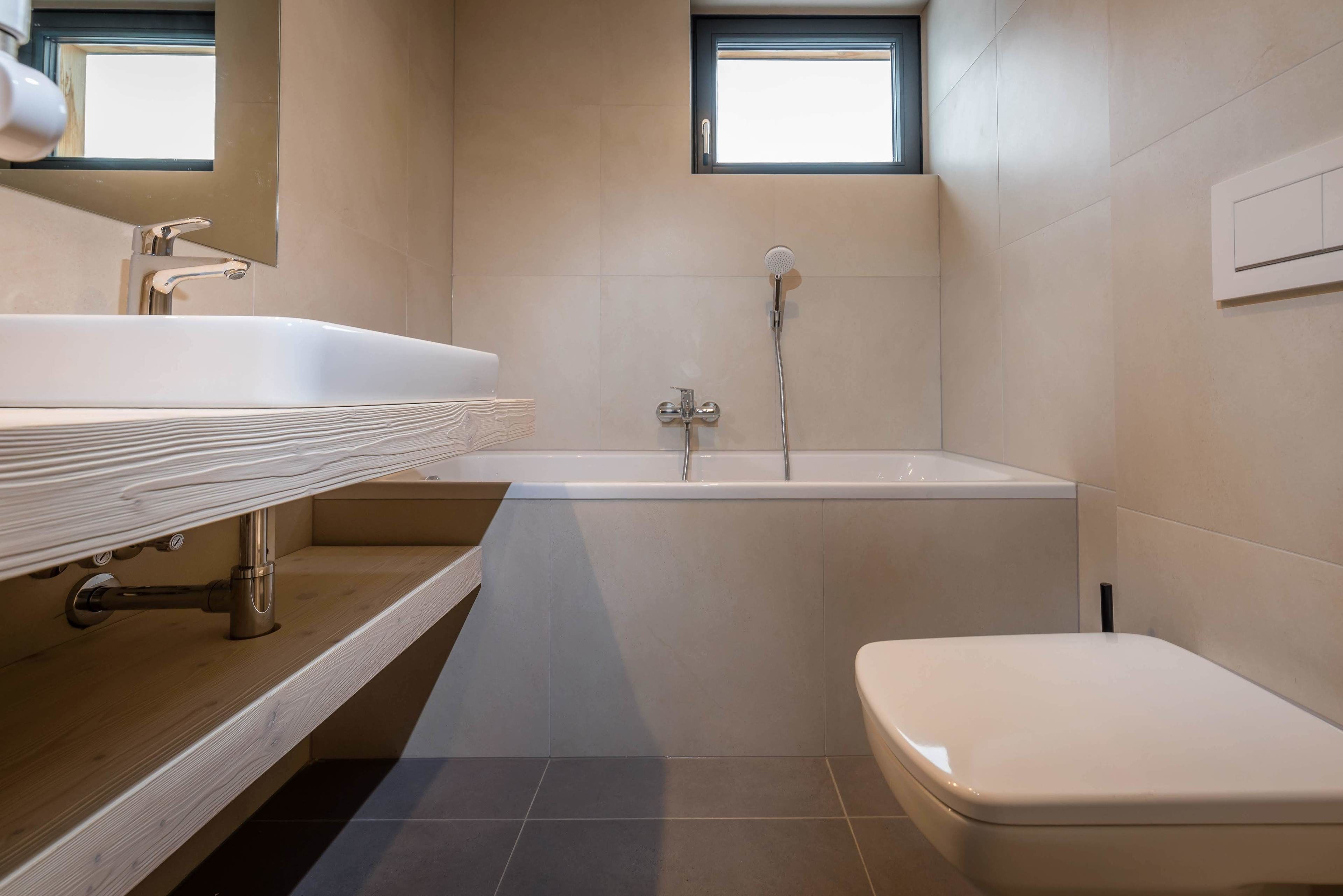 Un baño moderno con bañera, inodoro y lavabo con encimera de madera.