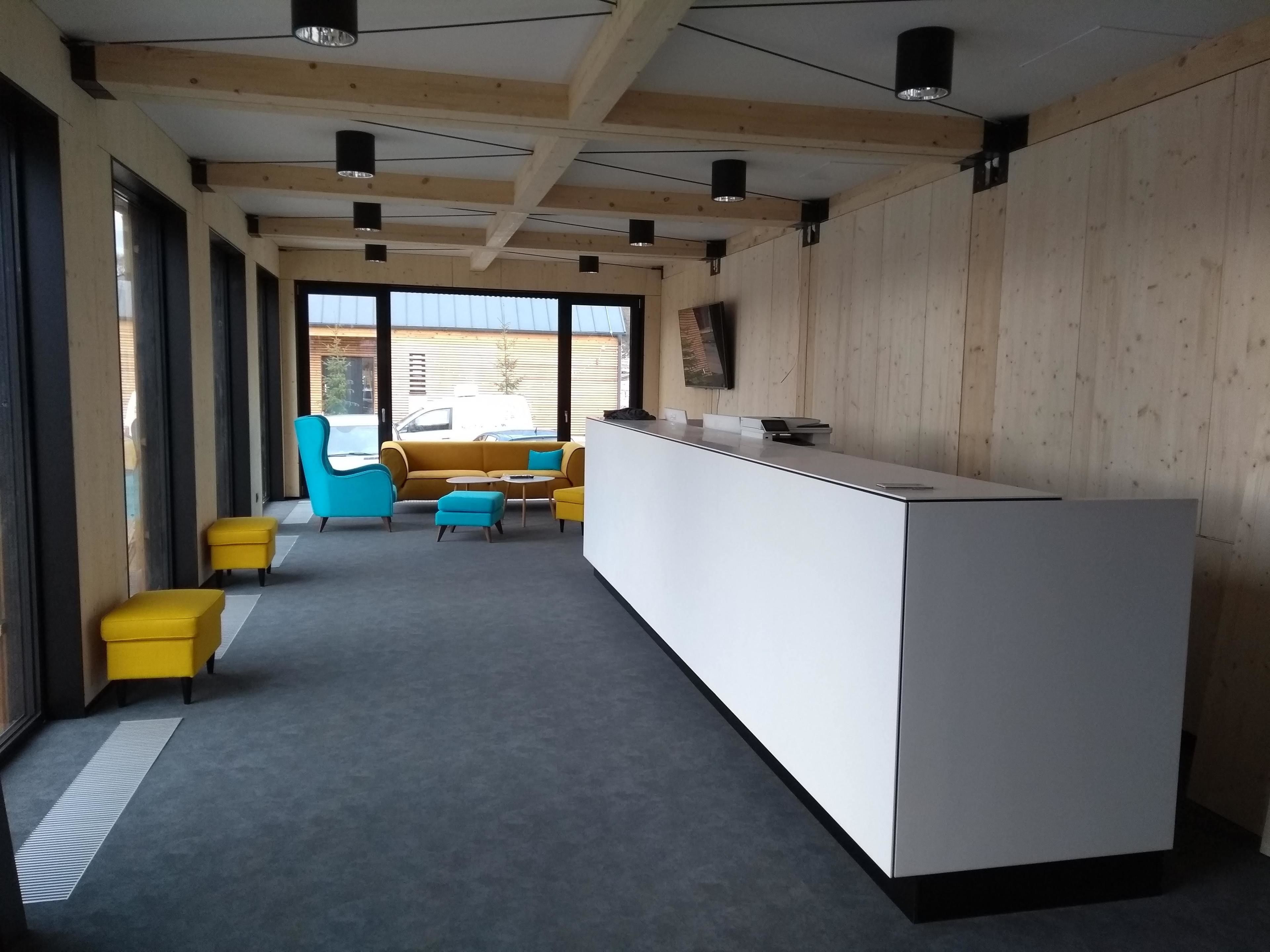 Een moderne receptie met een lange balie, houten wandpanelen en grote ramen met uitzicht op buiten.
