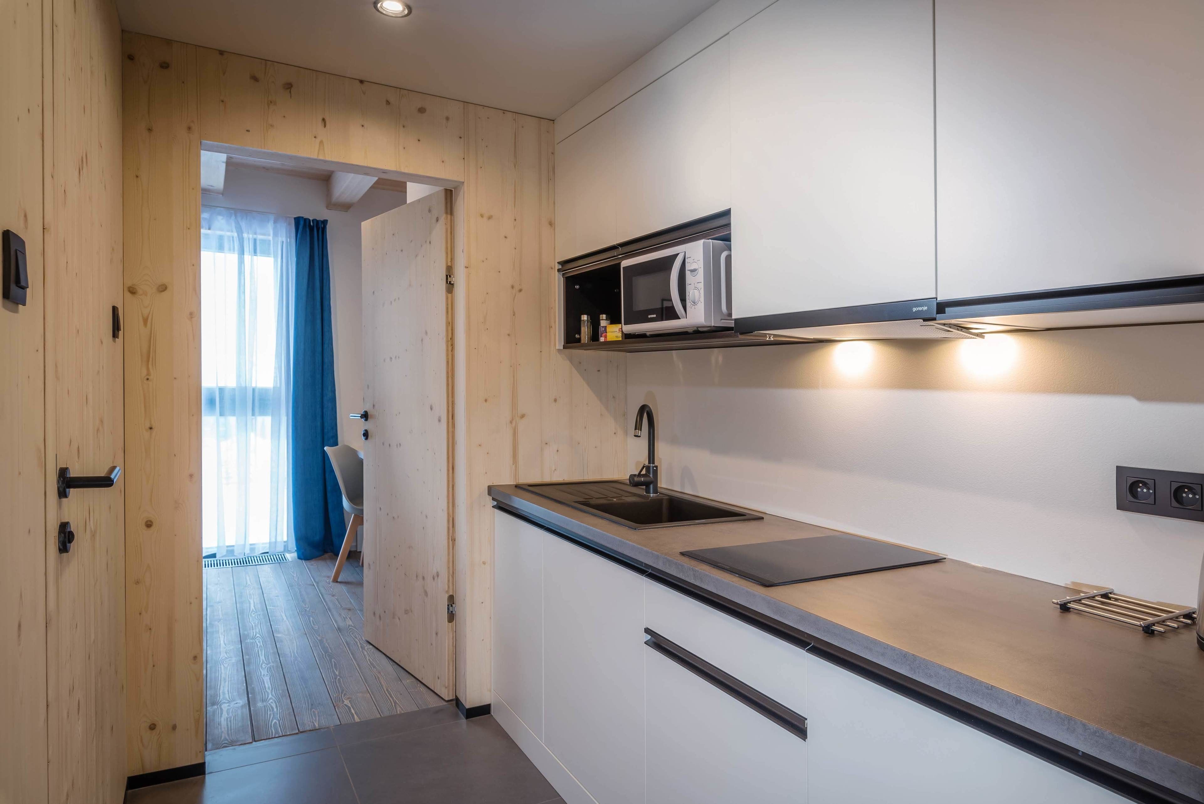 Una cucina moderna con forno a microonde integrato, lavello e piano di lavoro.