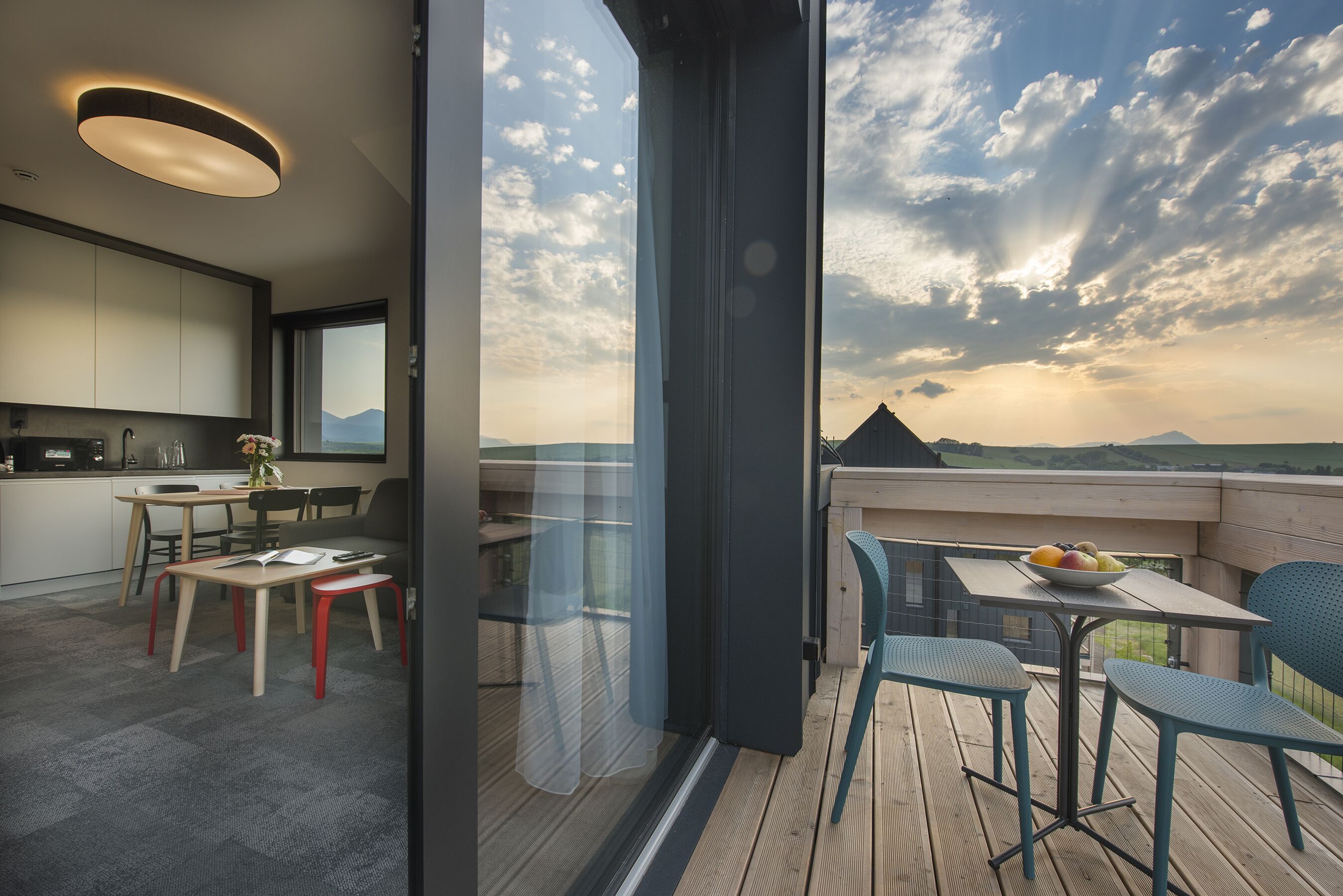 Une cuisine moderne avec un coin repas, un balcon doté d’une table et de chaises, et une vue sur les montagnes.