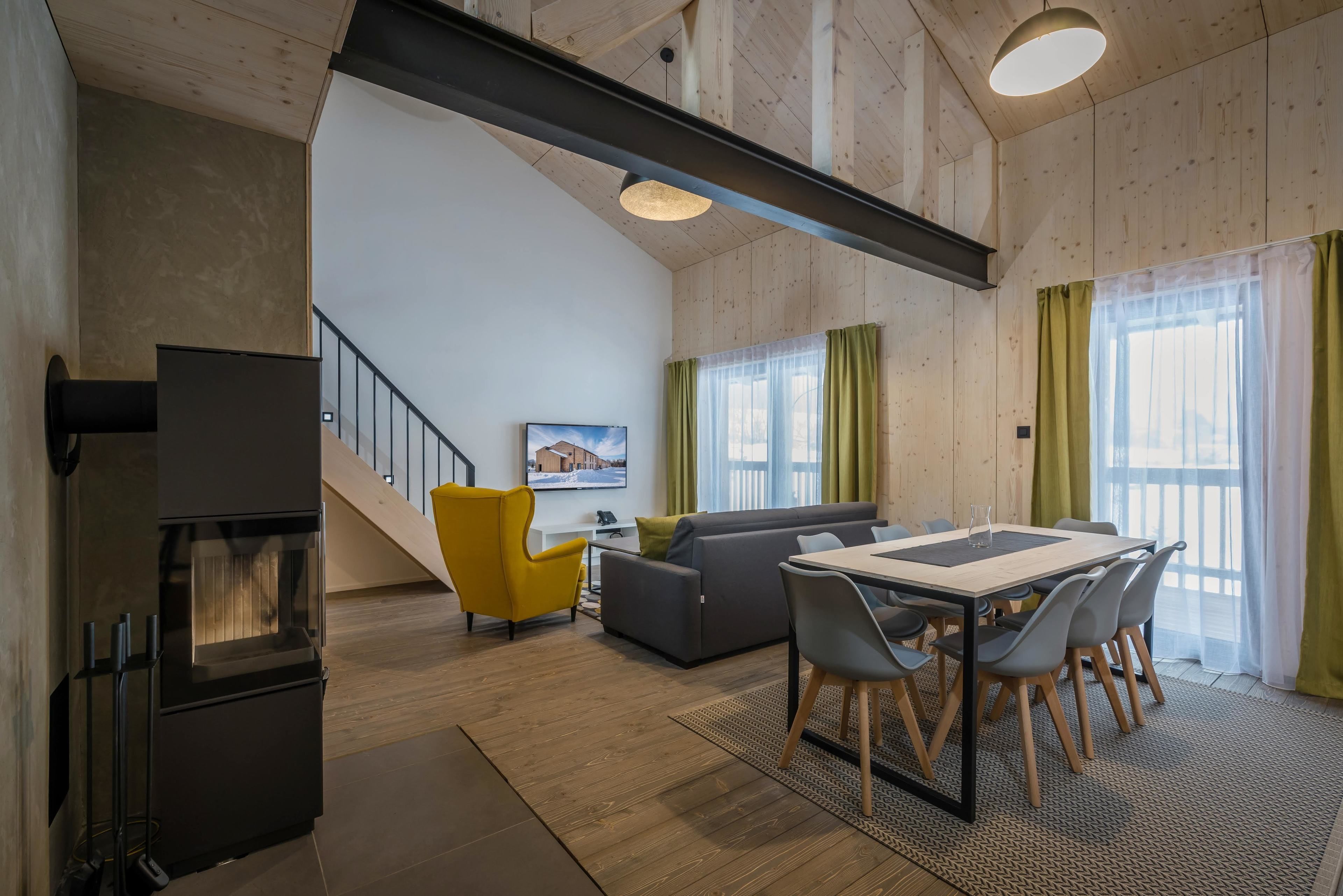 A modern living room with a sofa, dining table, chairs, and a fireplace.