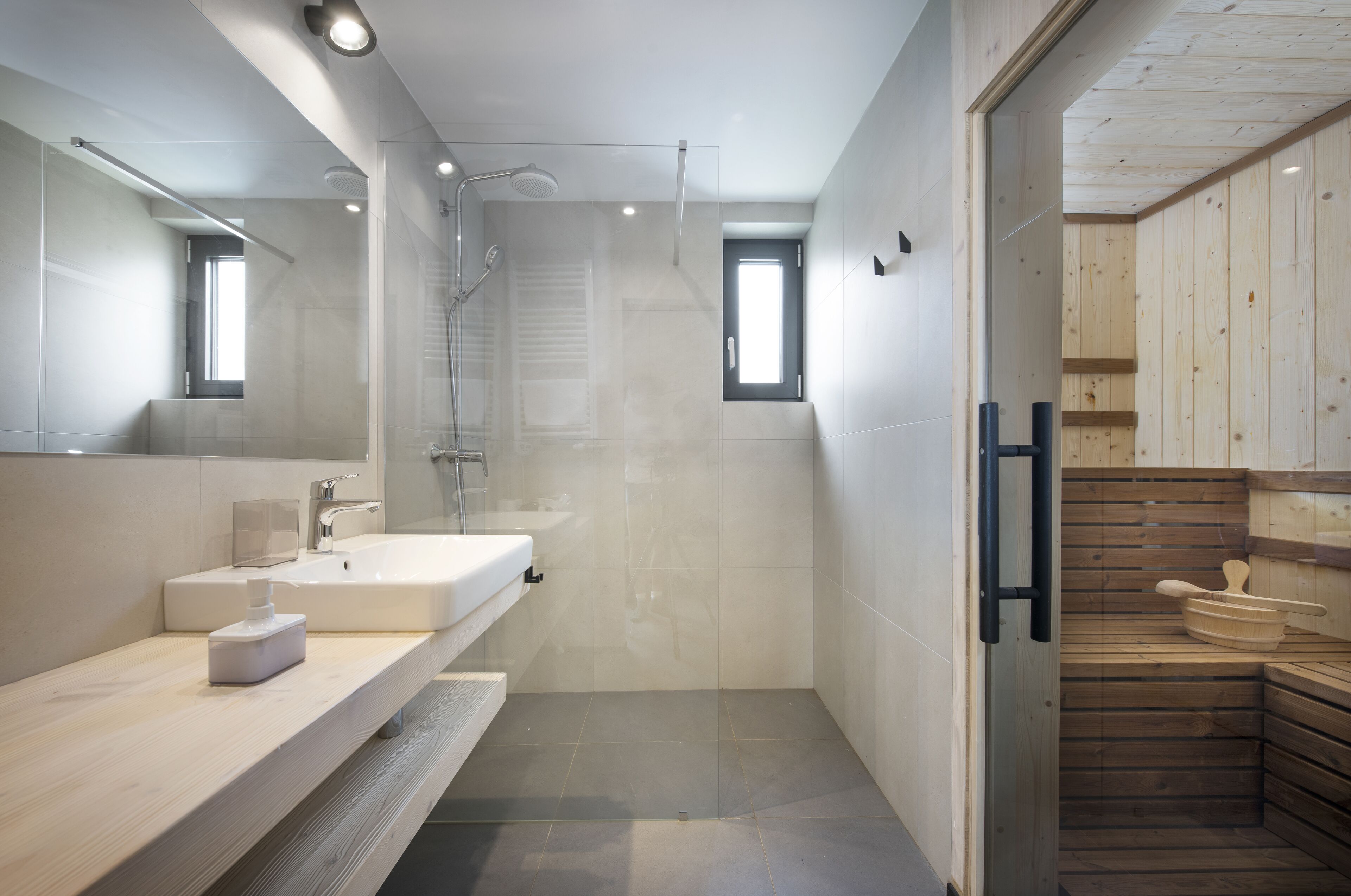 A modern bathroom with a large mirror, a sink, and a shower area.