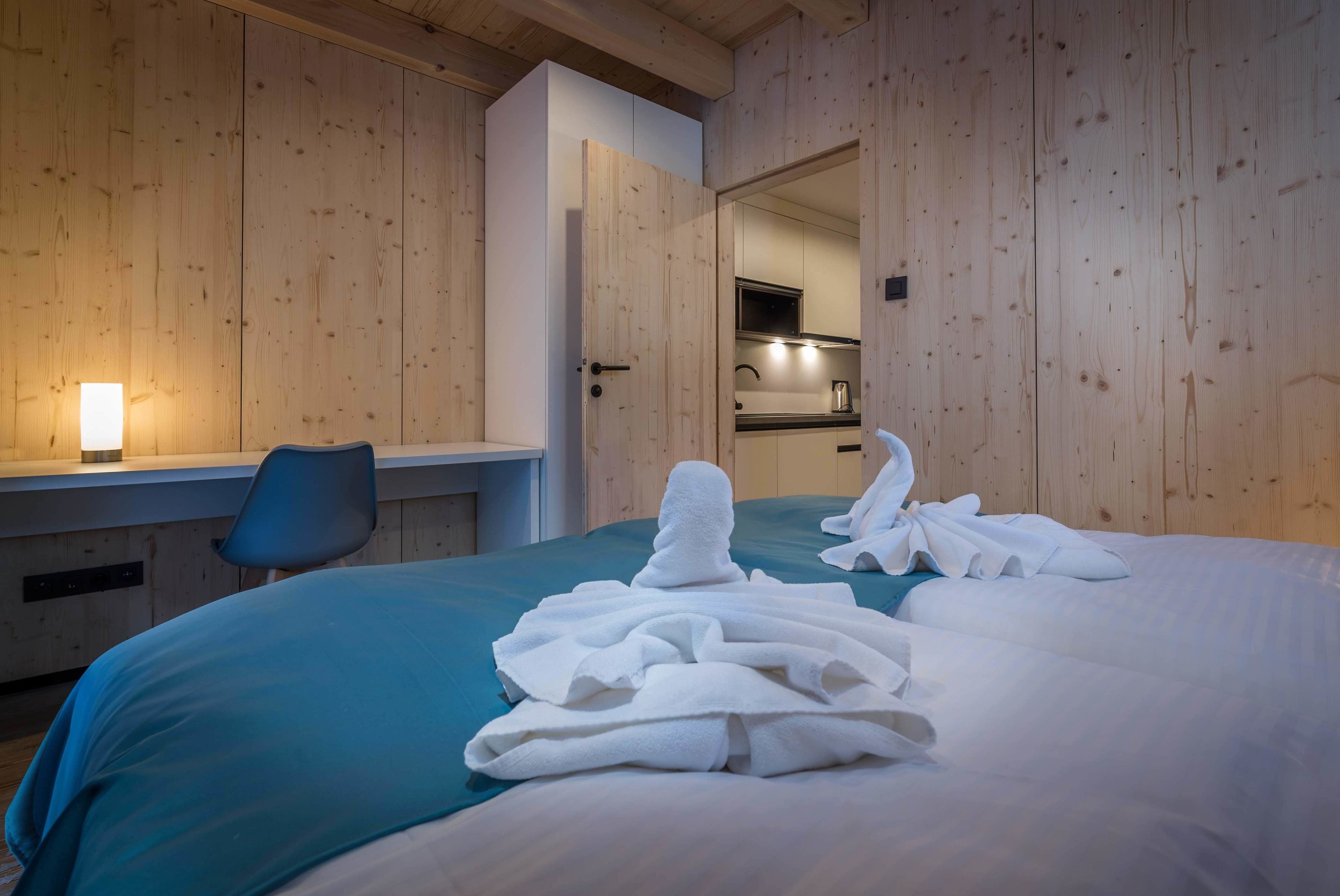 Habitación de hotel con cama, escritorio, silla y baño visible a través de una puerta abierta.