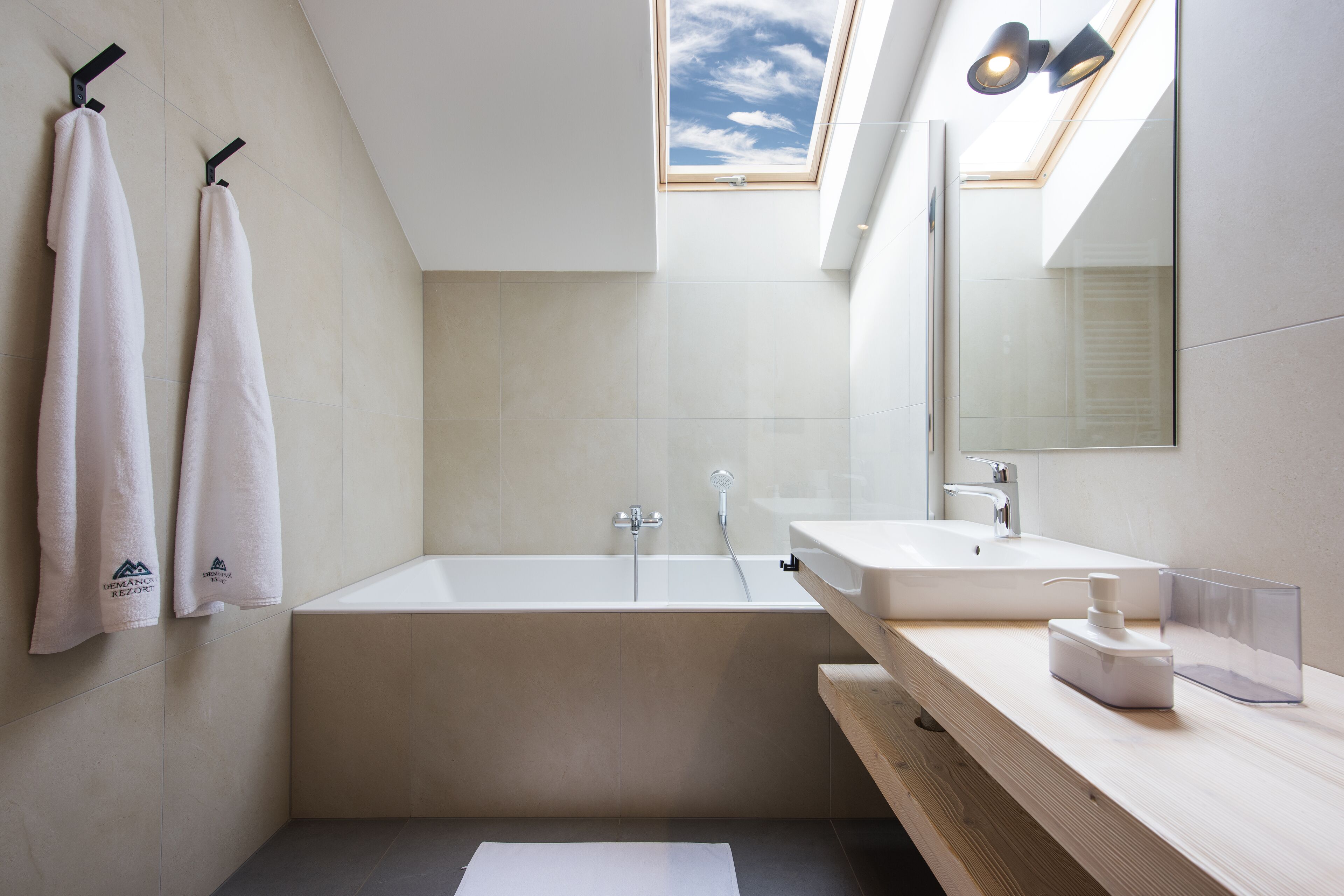 A modern bathroom with a freestanding bathtub, a large mirror, and a skylight.