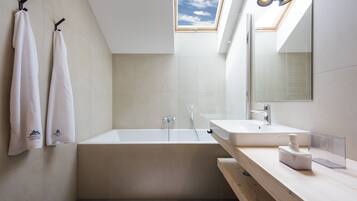 A modern bathroom with a freestanding bathtub, a large mirror, and a skylight.