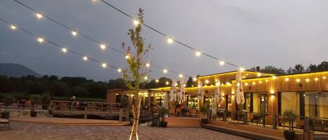 An outdoor restaurant with string lights, wooden tables, and chairs.