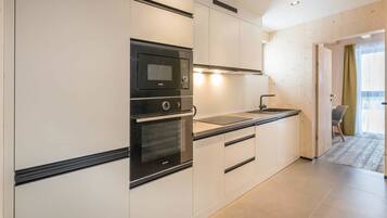 A modern kitchen with built-in appliances, a countertop, and a view to the dining area.