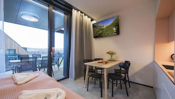 Una habitación de hotel moderna con balcón, comedor y kitchenette.