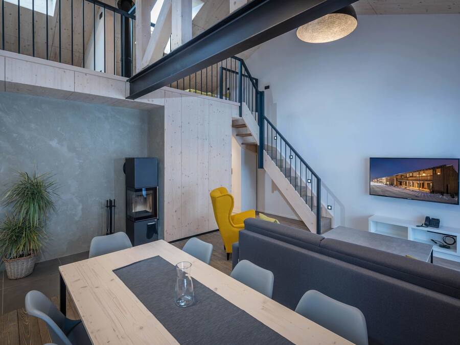 Un espacio habitable moderno con comedor, escalera y televisor montado.