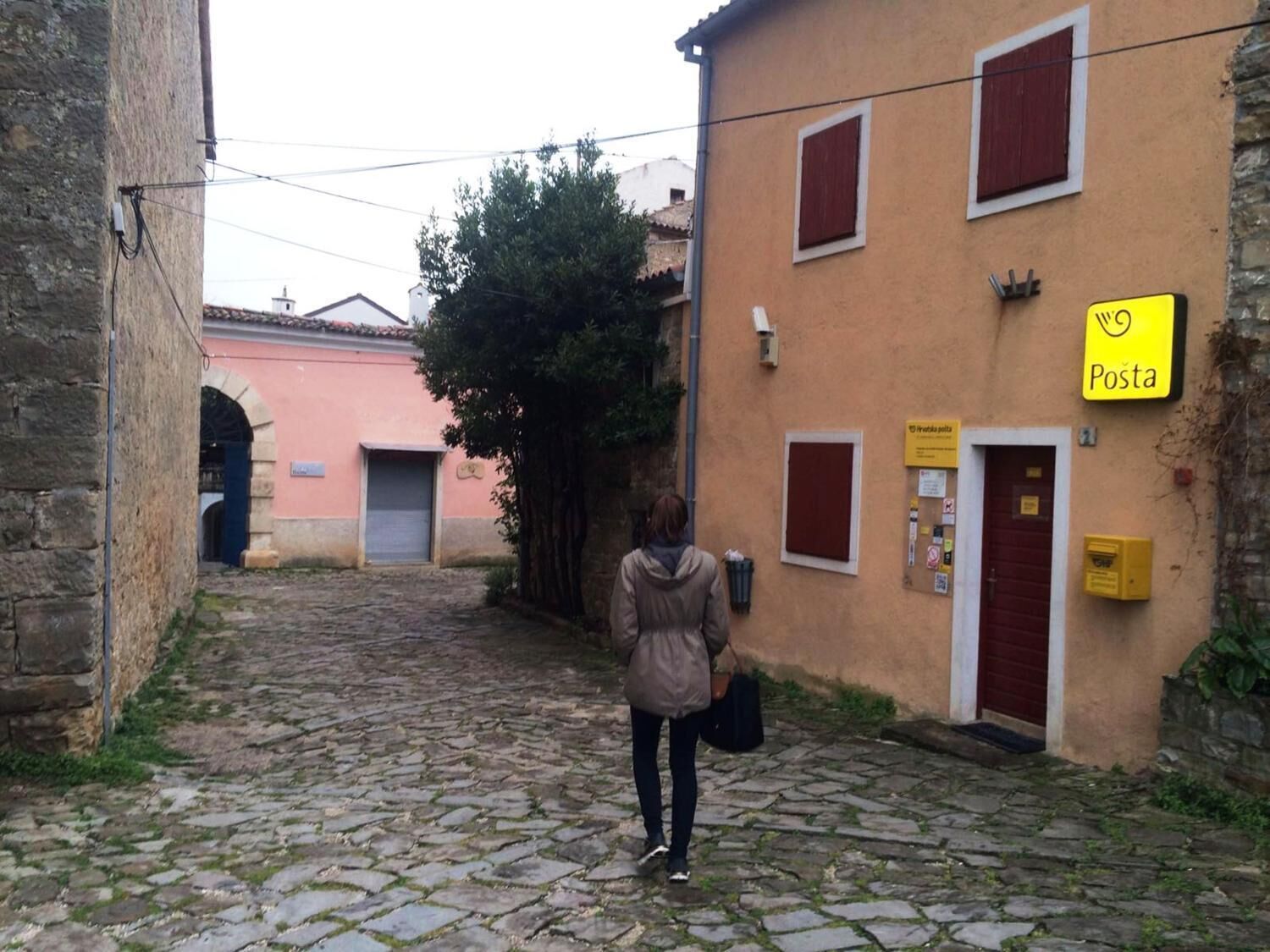 A cobblestone street with a building marked 'Posta' on the right.