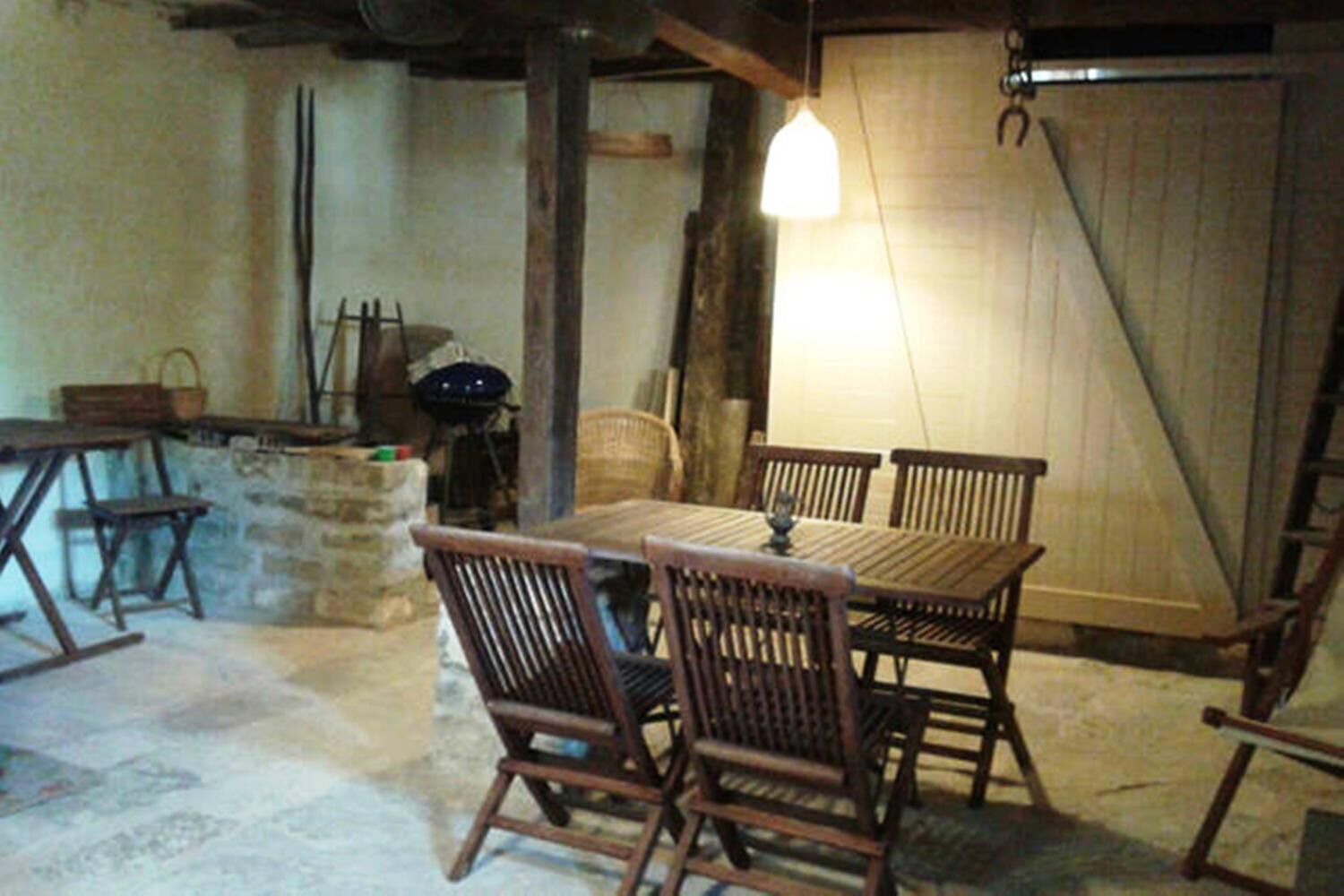 Un coin repas rustique avec une table et des chaises en bois, un luminaire suspendu et un mur en pierre.
