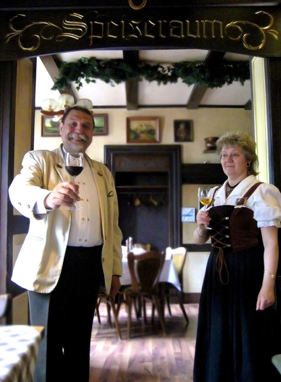 A man and a woman standing in a doorway with a sign above them.