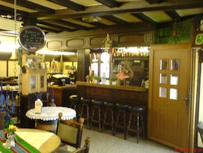 Un espace bar avec des tabourets, un comptoir et un menu écrit à la craie sur un tableau noir.