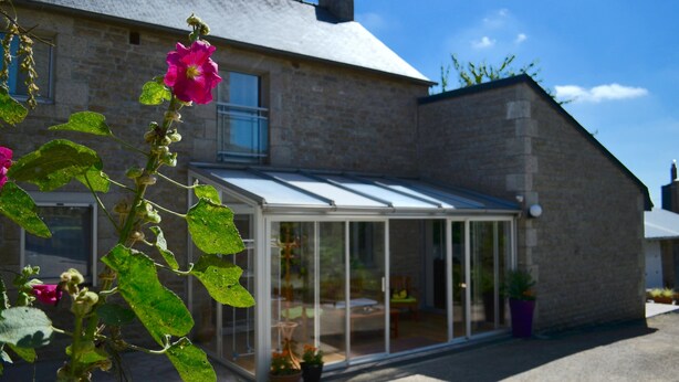 A house with a glass conservatory, a stone exterior, and a visible garden area. - Very nice renovated family house (DINAN)