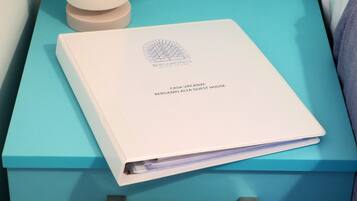 A white booklet titled "Bergamo Alta Guest House" on a teal-colored surface.