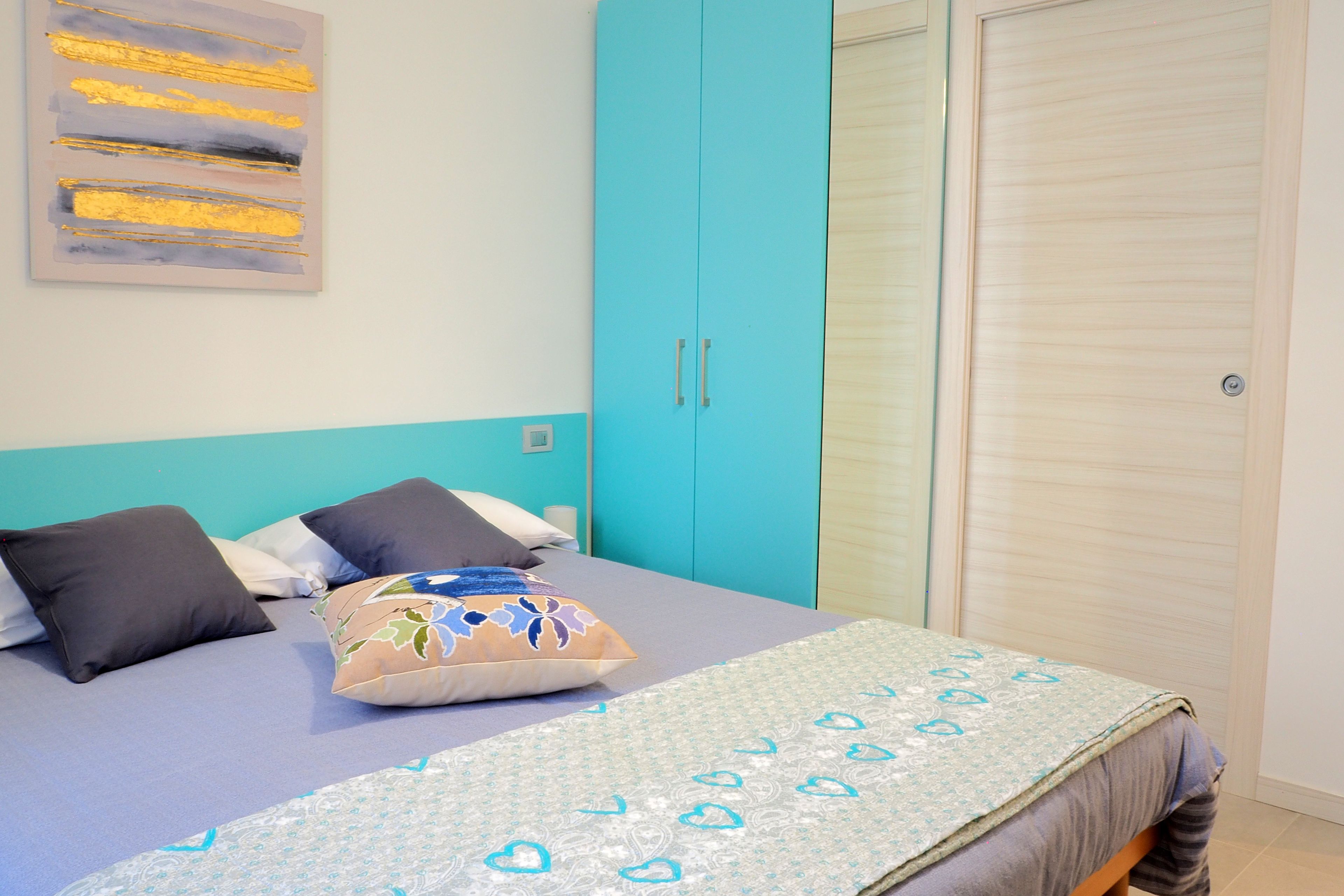 Ein Schlafzimmer mit einem Bett, einem blauen Kleiderschrank und einem Wandbild.