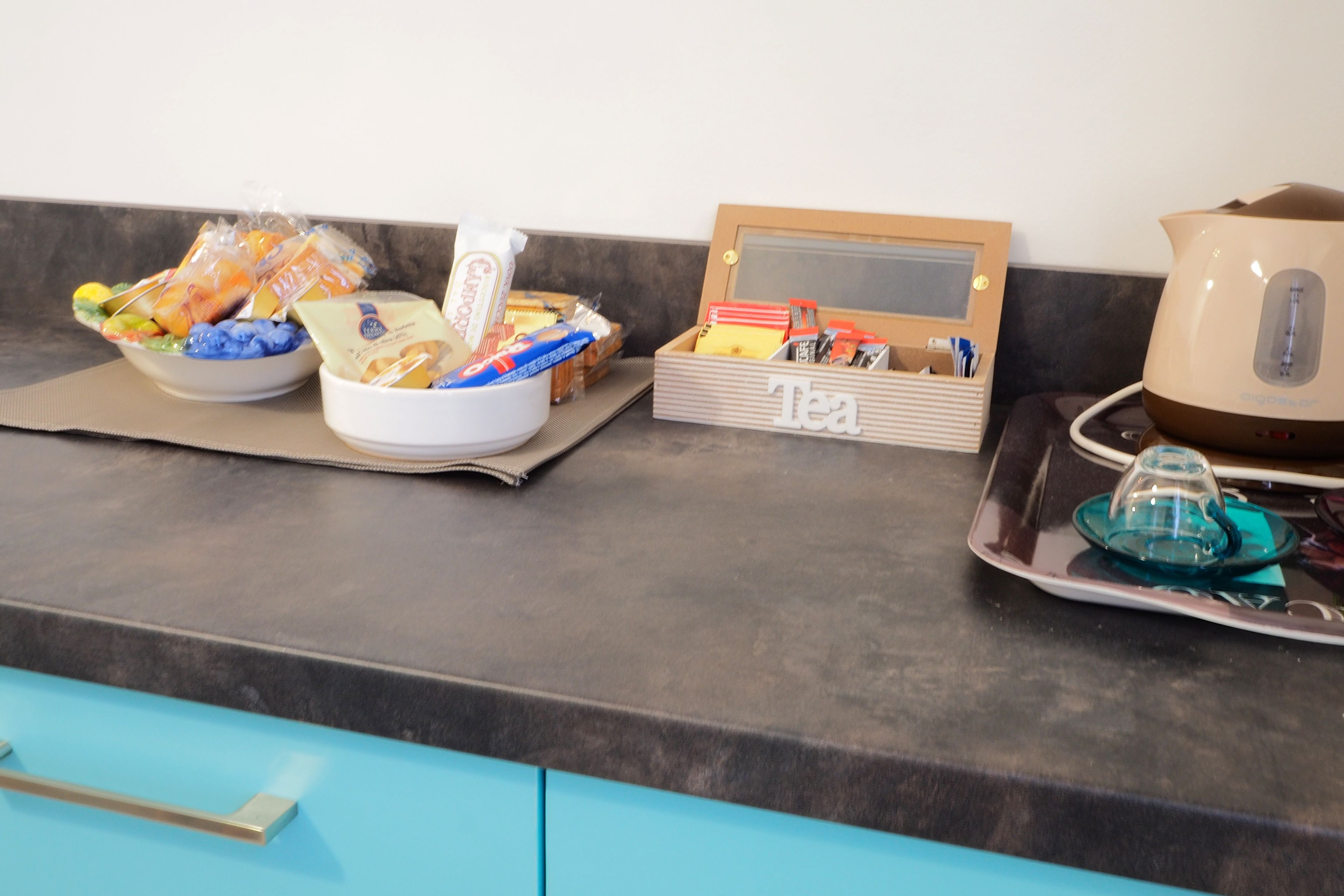 A kitchen counter with a tea station, a kettle, and various food items.
