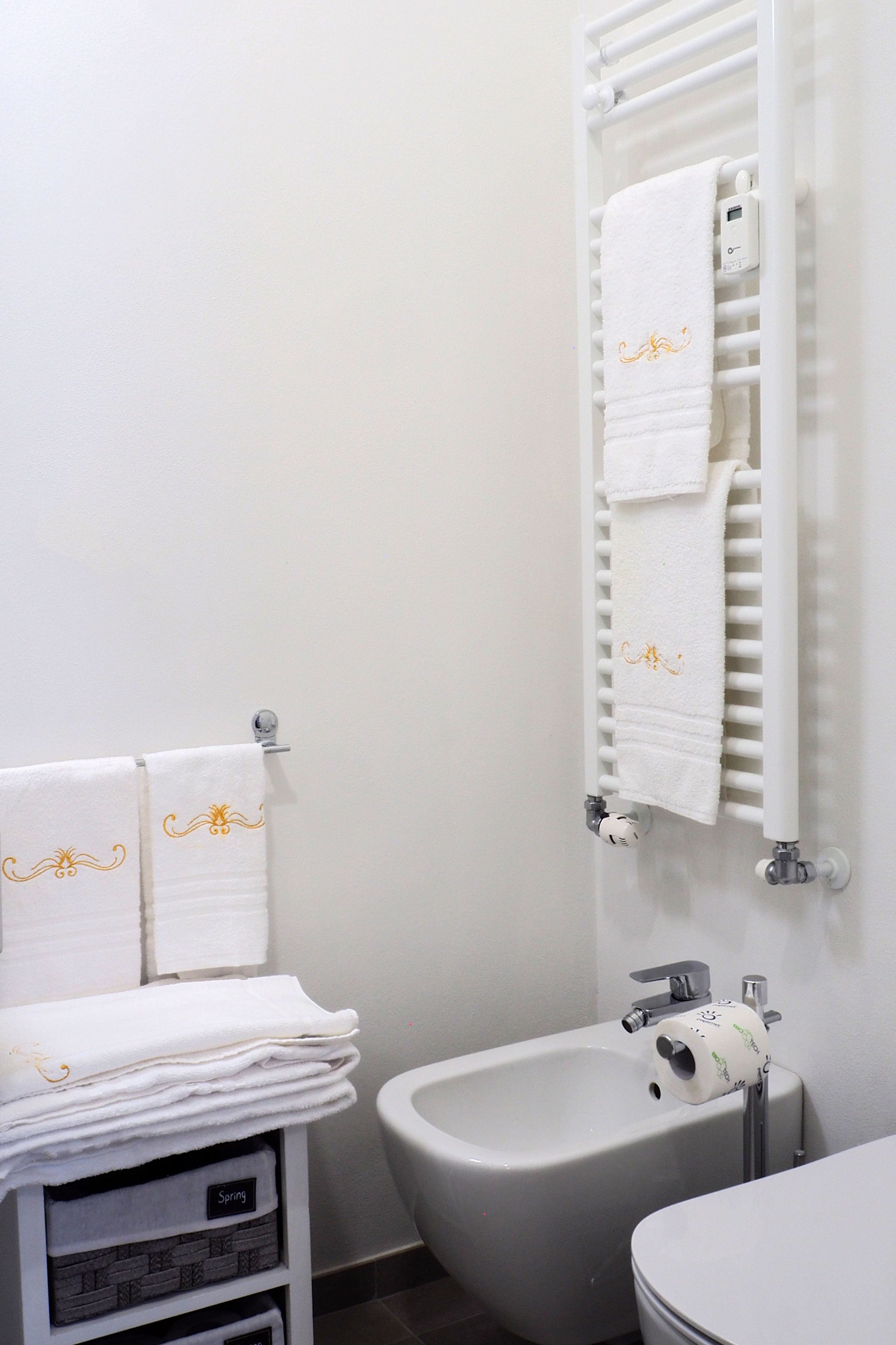 Une salle de bain équipée d’un bidet, de toilettes et d’un porte-serviettes avec des serviettes pliées.