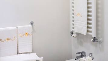 Une salle de bain équipée d’un bidet, de toilettes et d’un porte-serviettes avec des serviettes pliées.