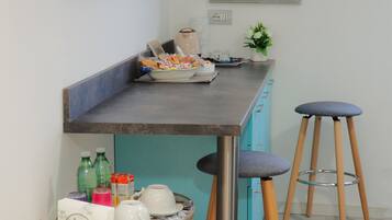 A kitchen area with a bar counter, stools, a small table with items, and two wall-mounted mirrors.